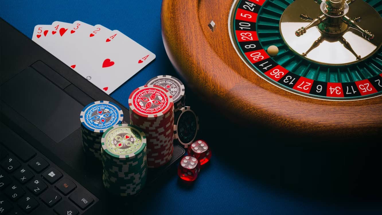 Laptop, roulette wheel, playing cards and colorful chips illustrate the intersection of technology and gambling in bot poker solutions